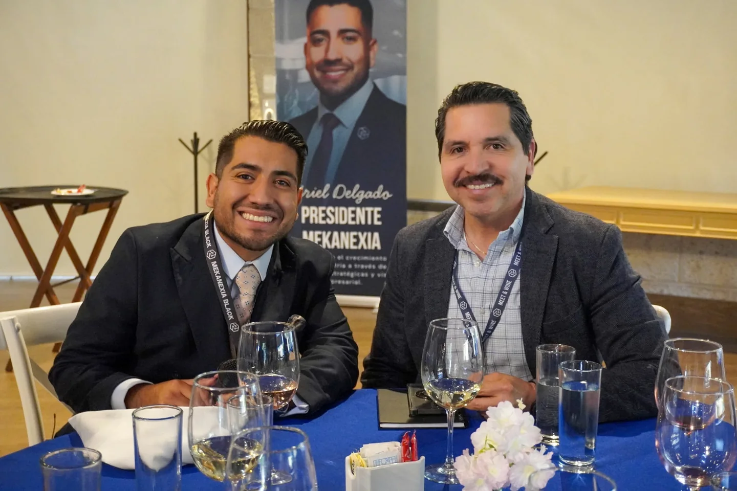 Dos asistentes con saco conversando en una mesa de Meet & Wine
